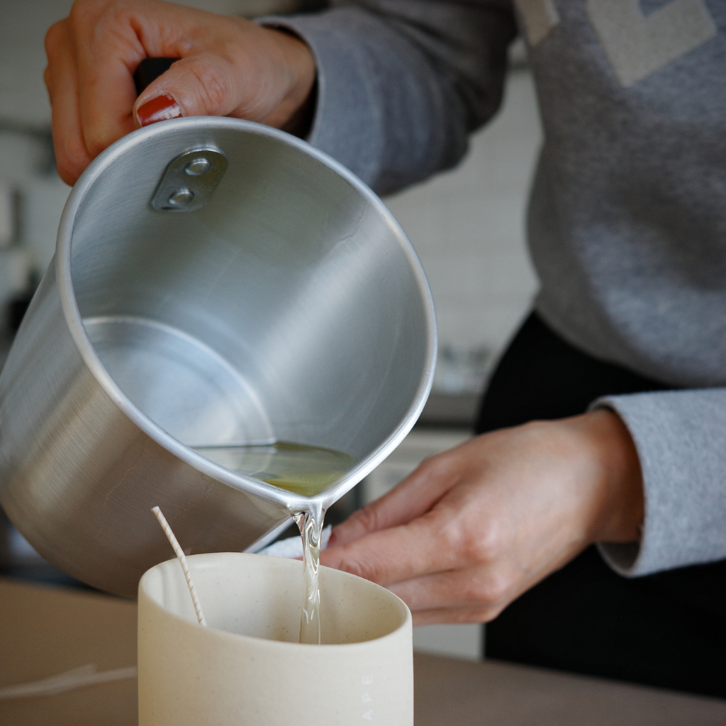 Person pouring liquid from a silver container into a white cup, duftlysworksho