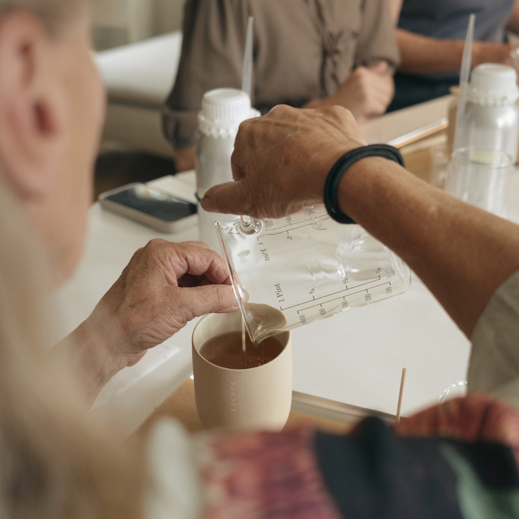 Pouring hot wax into a ceramic cup during Kensla Studio's candle making workshop in Oslo.